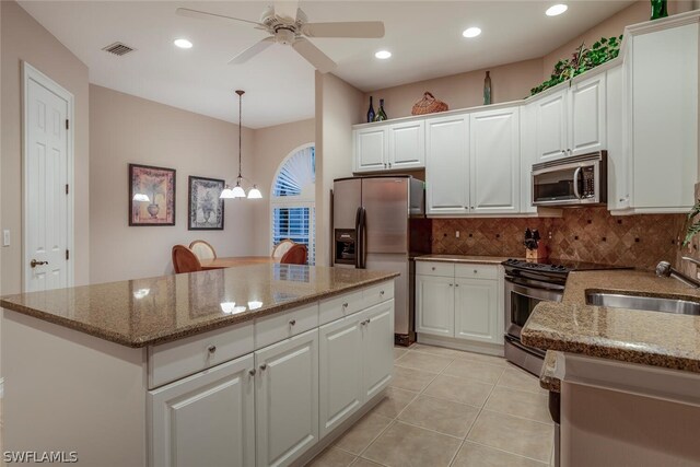 kitchen with hanging light fixtures, appliances with stainless steel finishes, a center island, and white cabinets