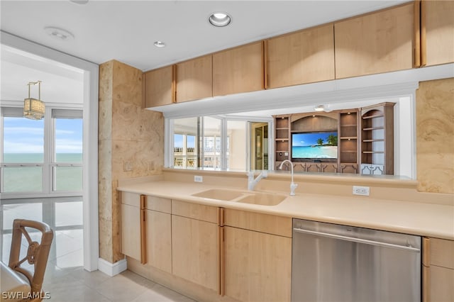 kitchen with light tile floors, light brown cabinetry, hanging light fixtures, dishwasher, and sink