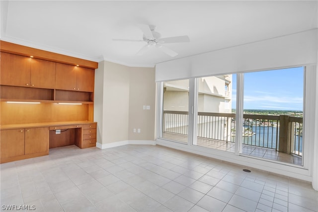 unfurnished living room with crown molding, ceiling fan, light tile floors, and built in desk