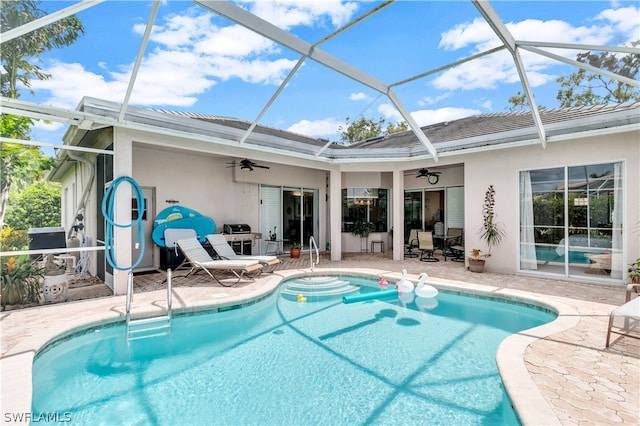 view of swimming pool featuring glass enclosure, ceiling fan, and a patio