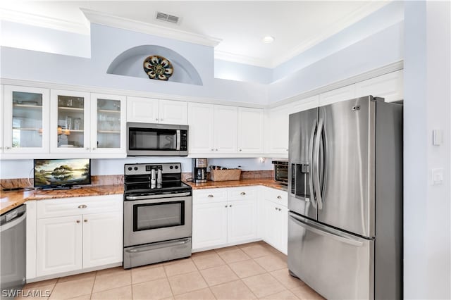 kitchen with light tile floors, white cabinets, ornamental molding, and stainless steel appliances