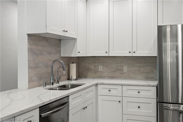 kitchen with white cabinetry, stainless steel appliances, sink, and light stone countertops