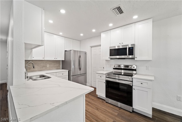 kitchen with stainless steel appliances, dark wood-type flooring, white cabinetry, and light stone counters