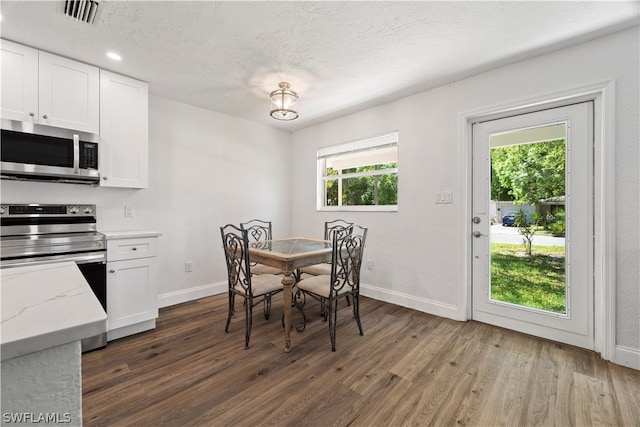 dining room with plenty of natural light, a textured ceiling, and dark hardwood / wood-style flooring