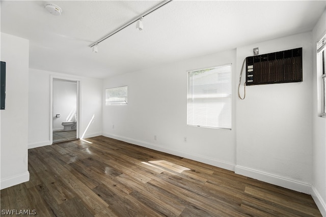 interior space featuring a wall mounted air conditioner, track lighting, and dark wood-type flooring