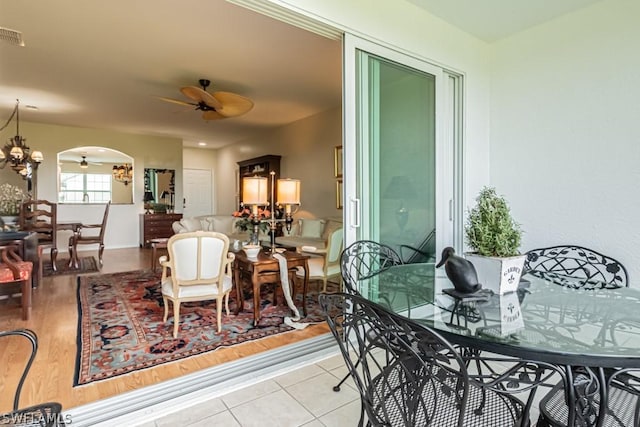 tiled dining space with ceiling fan with notable chandelier