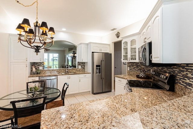 kitchen with sink, an inviting chandelier, appliances with stainless steel finishes, light stone countertops, and white cabinets