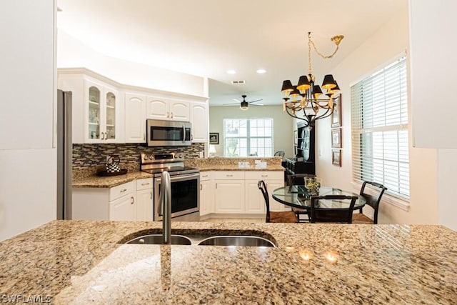 kitchen featuring white cabinetry, appliances with stainless steel finishes, pendant lighting, and ceiling fan with notable chandelier