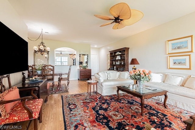 living room with light hardwood / wood-style floors and ceiling fan with notable chandelier