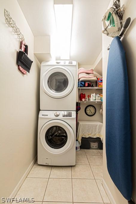 clothes washing area featuring stacked washing maching and dryer and light tile patterned floors