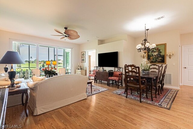 living room featuring ceiling fan with notable chandelier and light hardwood / wood-style flooring