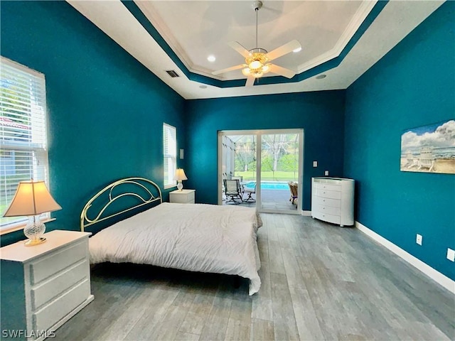 bedroom featuring access to outside, a raised ceiling, multiple windows, and visible vents