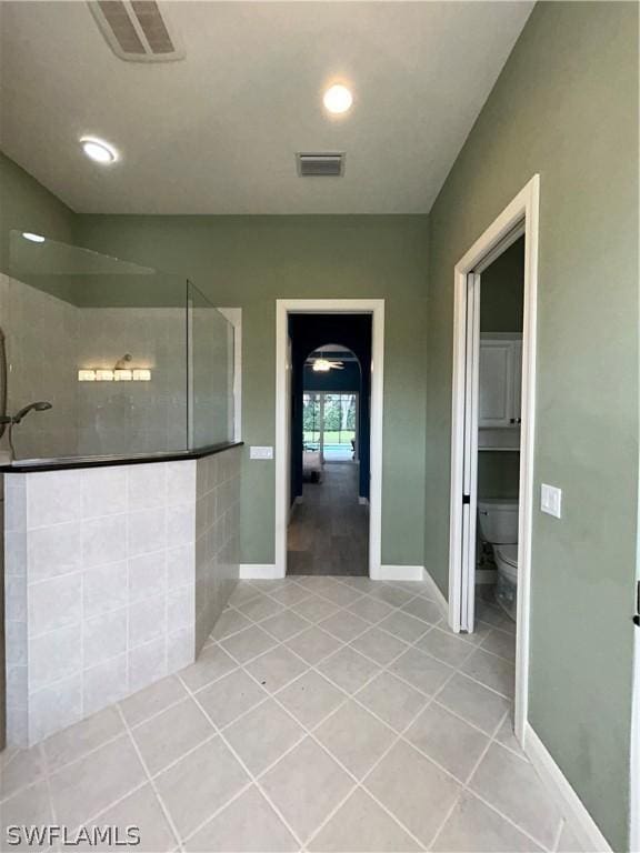 bathroom with baseboards, visible vents, toilet, tile patterned floors, and a walk in shower