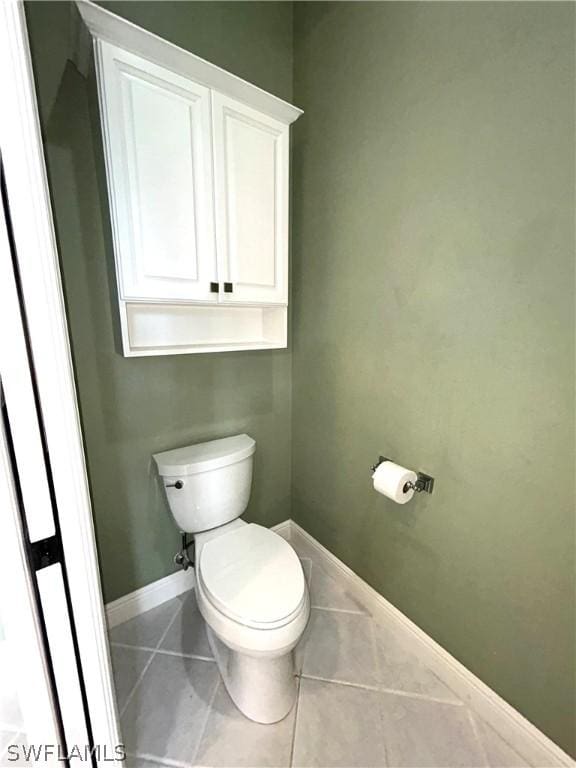 bathroom featuring toilet, tile patterned flooring, and baseboards