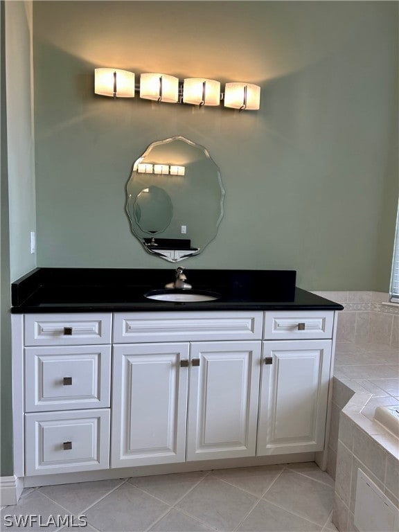 bathroom featuring a relaxing tiled tub, vanity, and tile patterned flooring