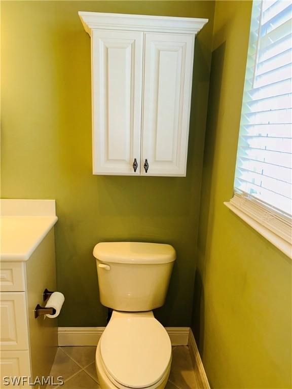 bathroom with toilet, tile patterned floors, baseboards, and vanity