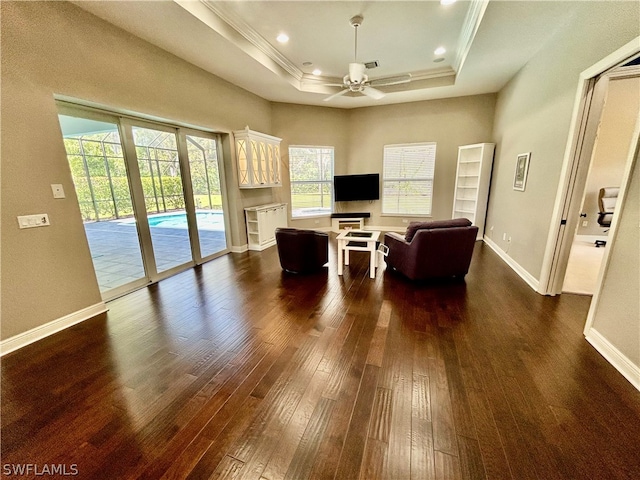 unfurnished living room with ceiling fan, dark hardwood / wood-style floors, a wealth of natural light, and a tray ceiling