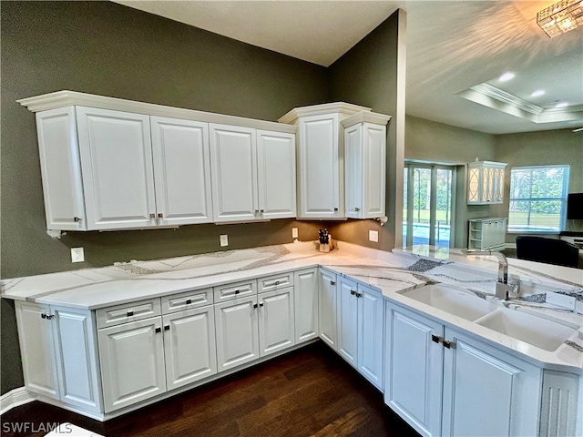 kitchen featuring dark wood-type flooring, white cabinetry, sink, kitchen peninsula, and light stone counters