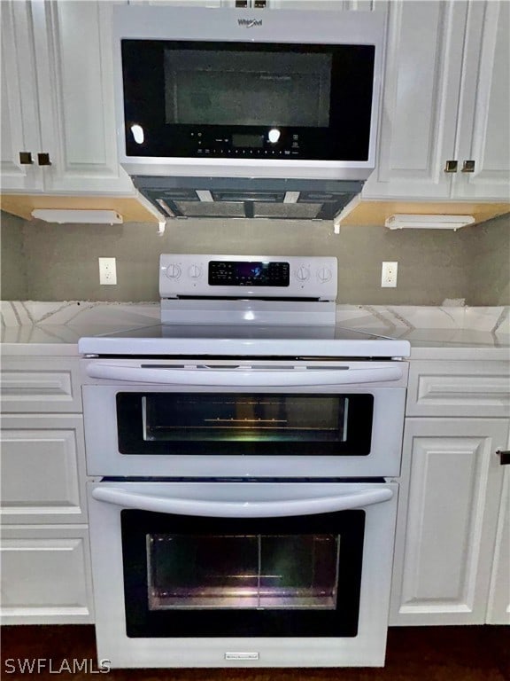 interior details with light stone countertops, white cabinetry, and appliances with stainless steel finishes