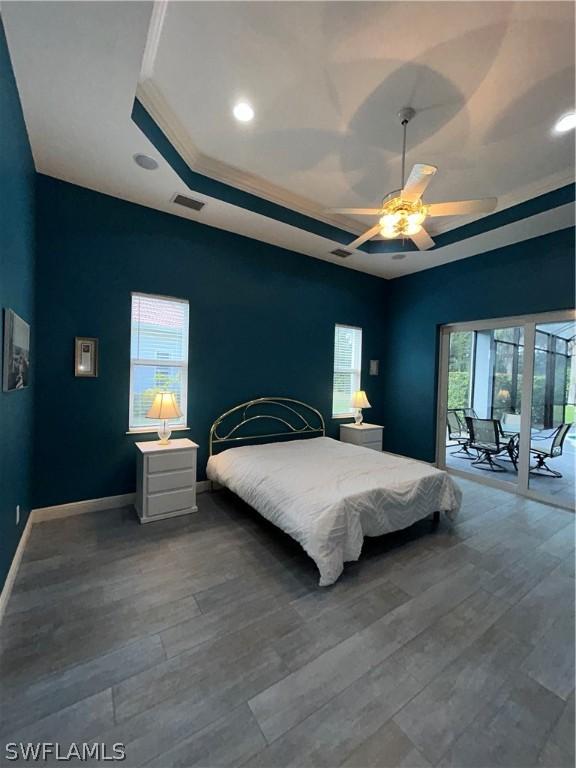 bedroom featuring multiple windows, a tray ceiling, and wood finished floors