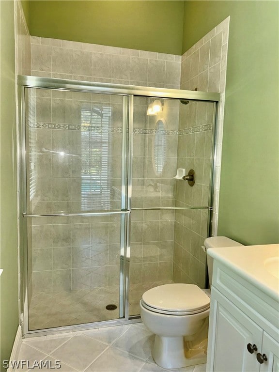 bathroom with toilet, tile patterned floors, a shower with door, and vanity