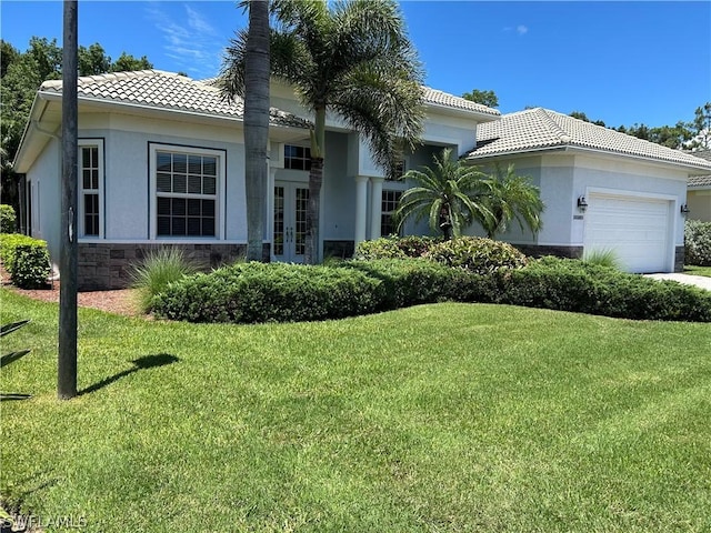 view of front of home with a garage, a tiled roof, french doors, stucco siding, and a front lawn