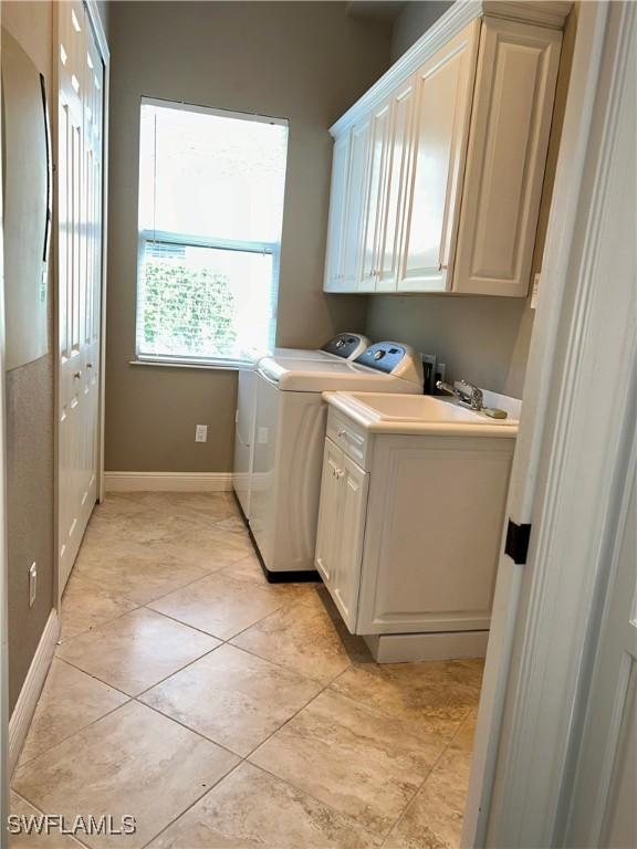 laundry room with light tile patterned floors, washer and clothes dryer, cabinet space, and baseboards