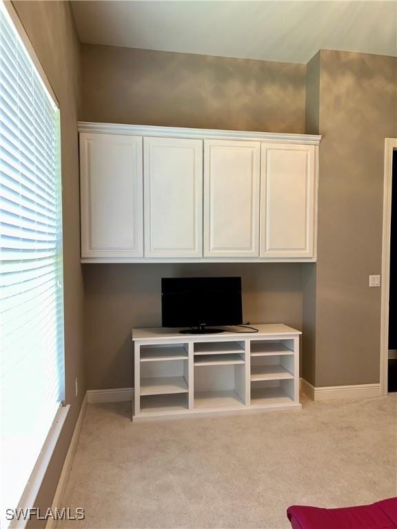 interior space featuring light colored carpet and baseboards