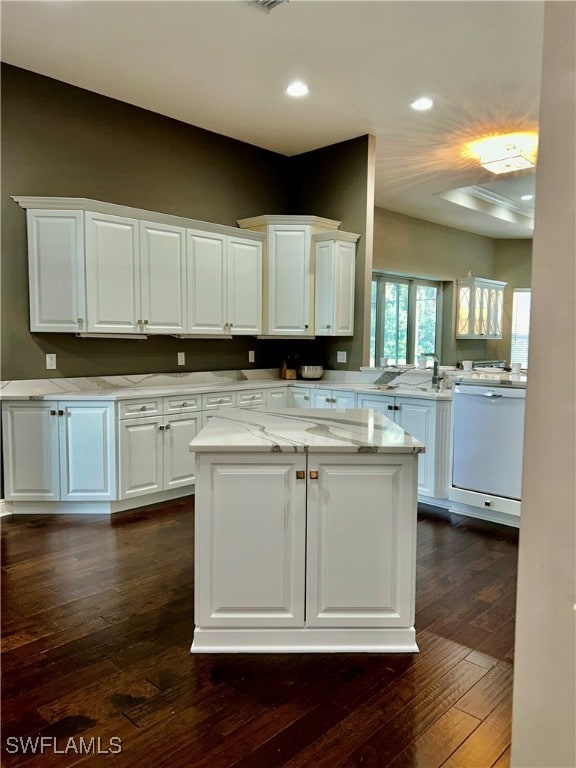 kitchen with white cabinetry, kitchen peninsula, dark wood-type flooring, dishwasher, and light stone counters