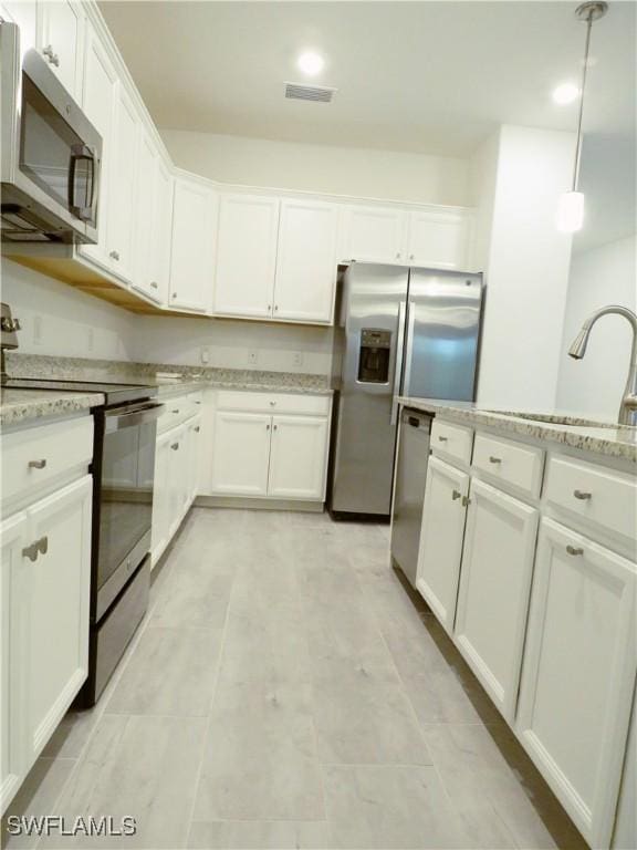 kitchen featuring light stone countertops, appliances with stainless steel finishes, white cabinetry, sink, and hanging light fixtures