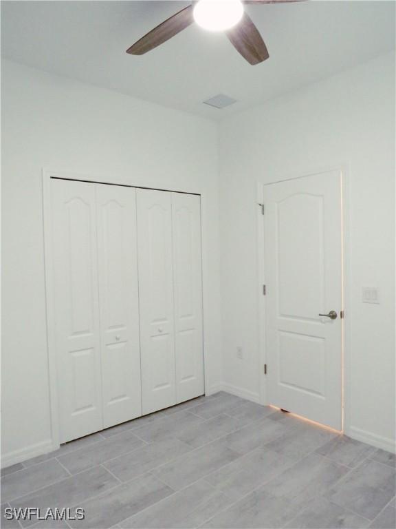 unfurnished bedroom featuring ceiling fan and a closet