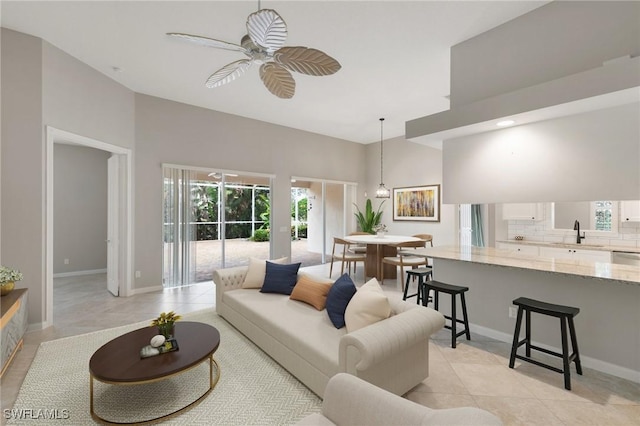 tiled living room featuring a towering ceiling, ceiling fan, and sink