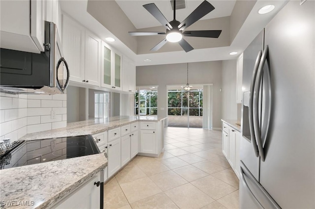 kitchen with white cabinets, ceiling fan with notable chandelier, light tile patterned floors, appliances with stainless steel finishes, and light stone counters