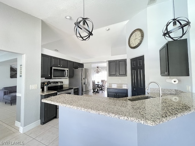 kitchen with a chandelier, stainless steel appliances, kitchen peninsula, sink, and light stone counters