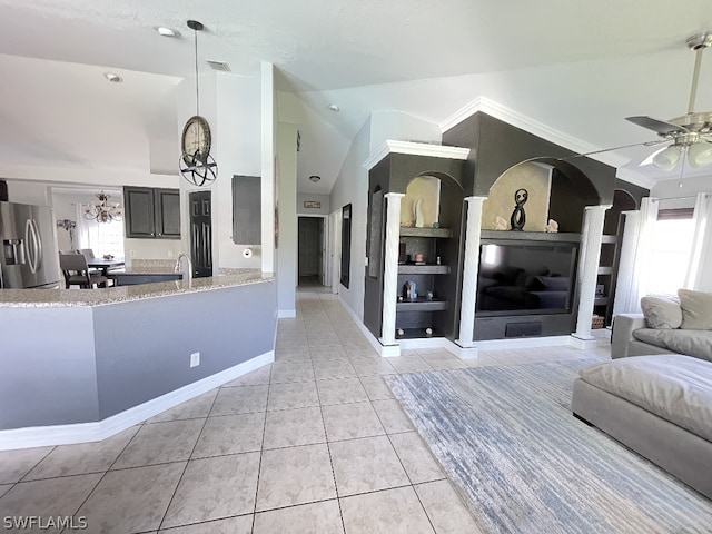 kitchen with light tile flooring, kitchen peninsula, ceiling fan with notable chandelier, stainless steel fridge with ice dispenser, and built in features