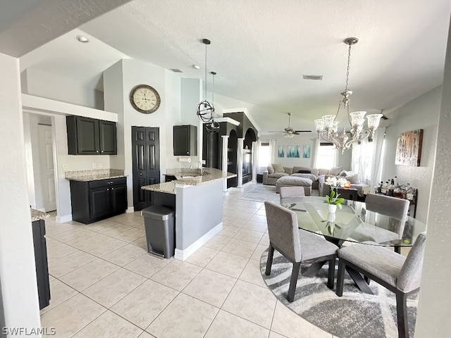 kitchen featuring light stone countertops, ceiling fan with notable chandelier, light tile flooring, and pendant lighting