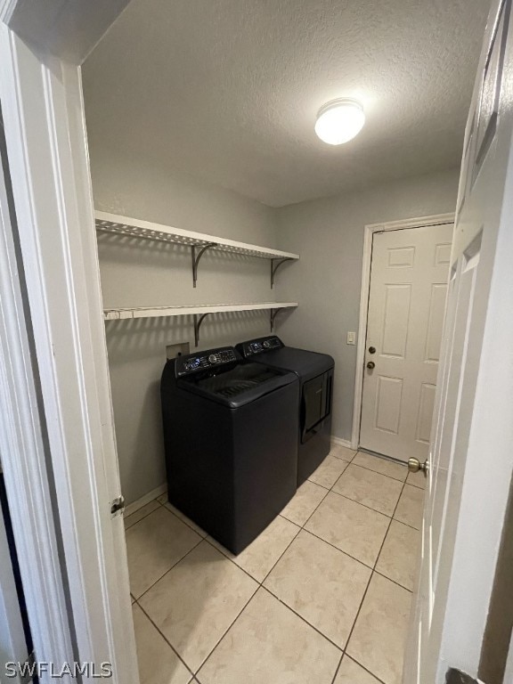 laundry area with light tile floors, washer and clothes dryer, and a textured ceiling