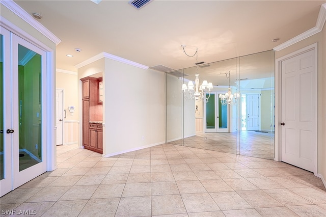 empty room with ornamental molding, french doors, and an inviting chandelier