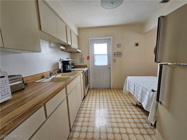 kitchen with light tile floors, range with electric stovetop, refrigerator, and sink