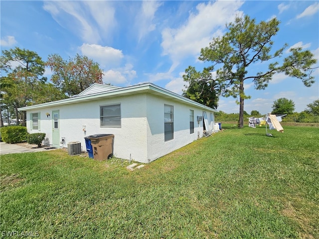 view of side of home featuring central air condition unit and a yard