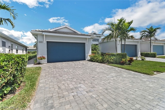 ranch-style house with a garage, decorative driveway, and stucco siding