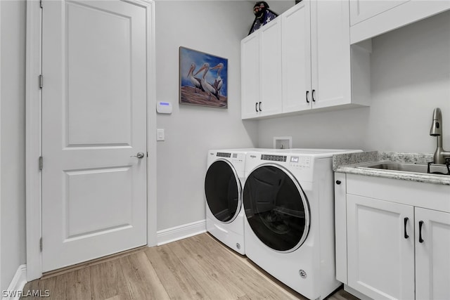 washroom with cabinets, sink, washer and dryer, and light wood-type flooring