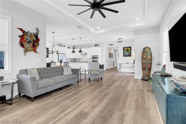 living area with recessed lighting, visible vents, baseboards, light wood-style floors, and a raised ceiling