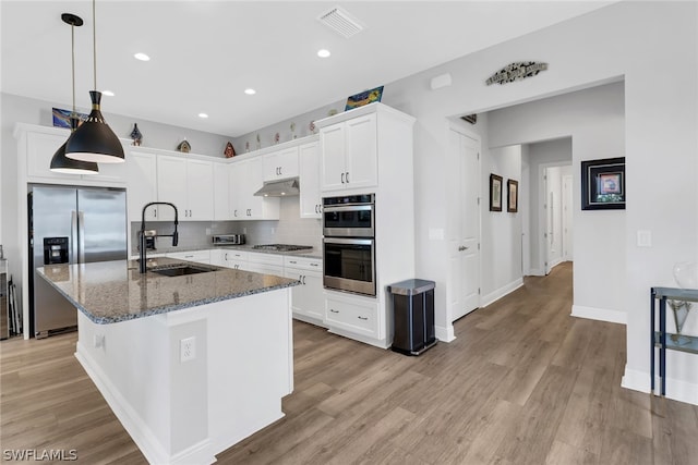 kitchen featuring decorative backsplash, stainless steel appliances, stone counters, white cabinetry, and a sink