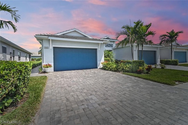 view of front facade featuring a garage, decorative driveway, and stucco siding