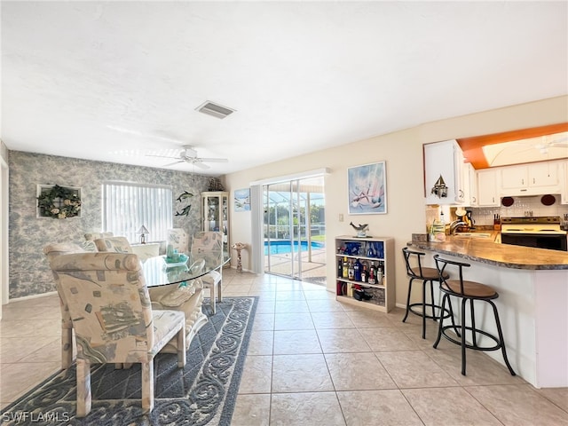 dining area with sink, ceiling fan, and light tile flooring