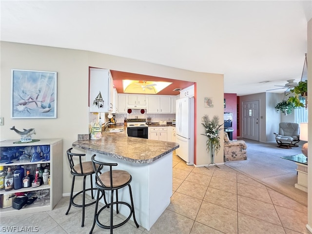 kitchen featuring white cabinetry, kitchen peninsula, white appliances, and light tile floors