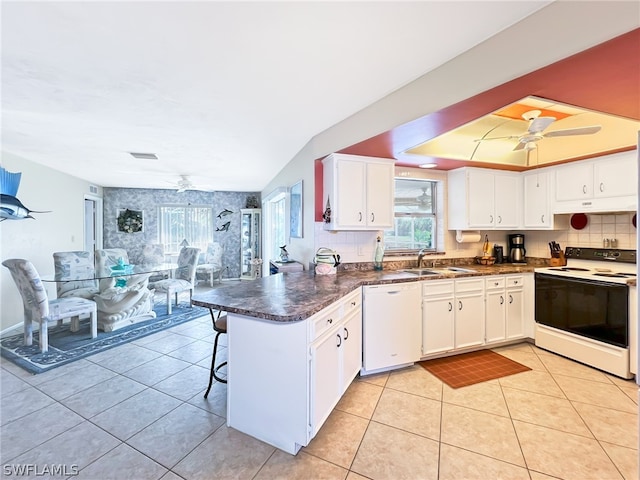 kitchen with kitchen peninsula, white appliances, ceiling fan, white cabinets, and a breakfast bar