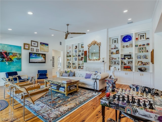 living room with lofted ceiling, light hardwood / wood-style floors, ceiling fan, and built in shelves