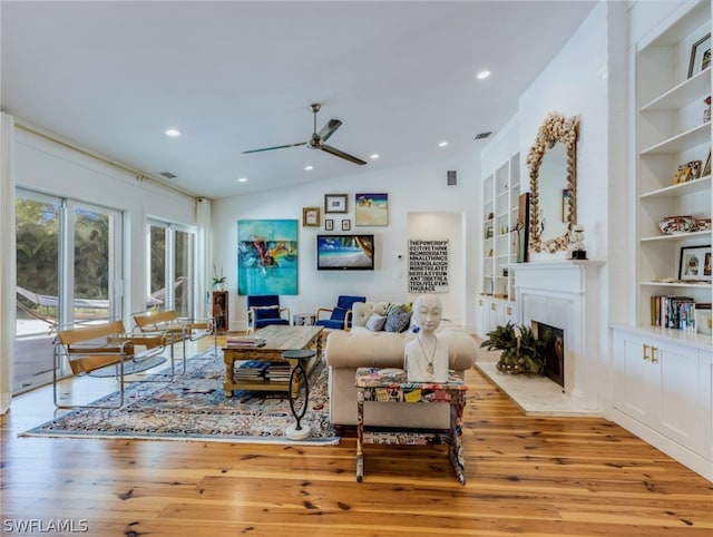 living room with built in features, lofted ceiling, ceiling fan, and light hardwood / wood-style flooring